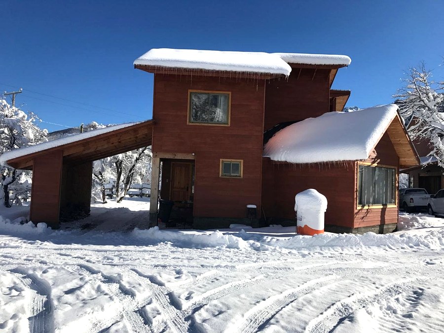 Exterior cabaña con nieve y cielo azul